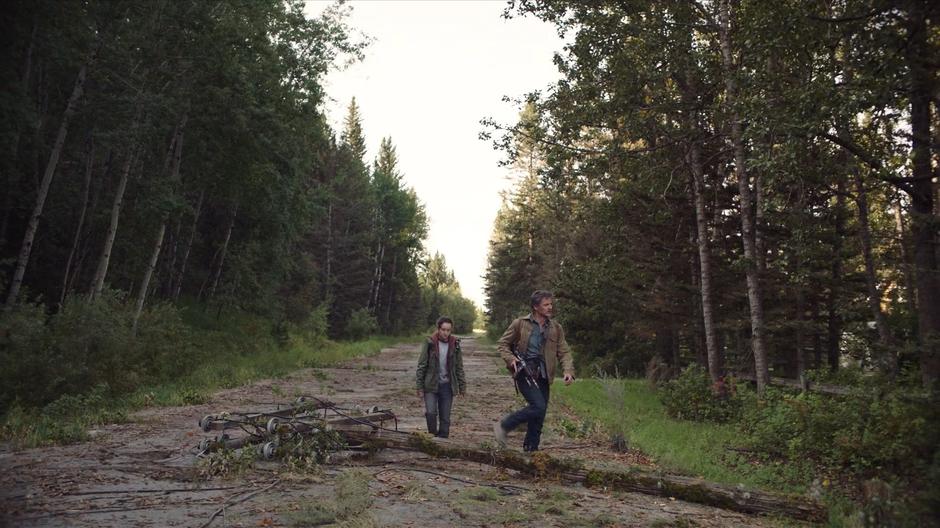 Joel and Ellie step across a downed electrical pole and head towards the store.