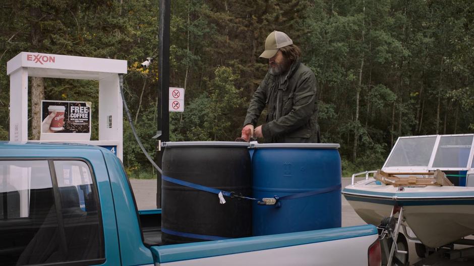 Bill pumps gas into large drums loaded into the back of his truck.