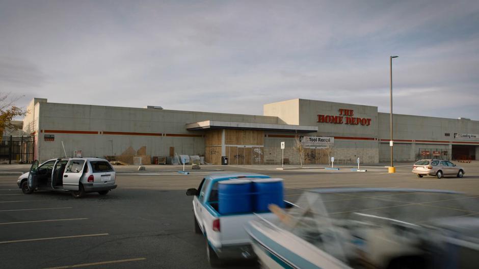 Bill drives his car towards the boarded up Home Depot.