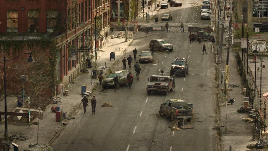 A revolutionary patrol drives down the street while others walk around.