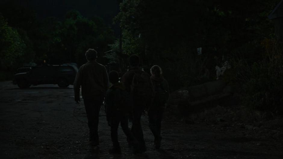 Joel, Sam, Henry, and Ellie walk around the street corner.