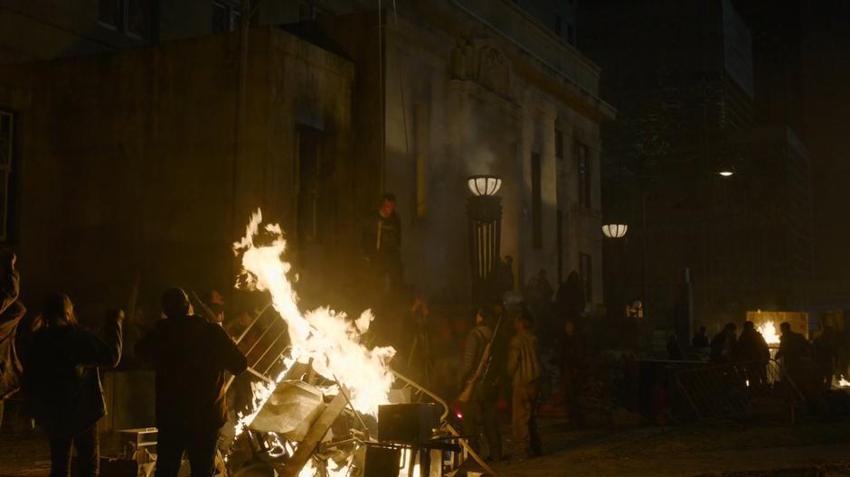 The revolutionaries string up a FEDRA officer next to a bonfire in front of the post office.