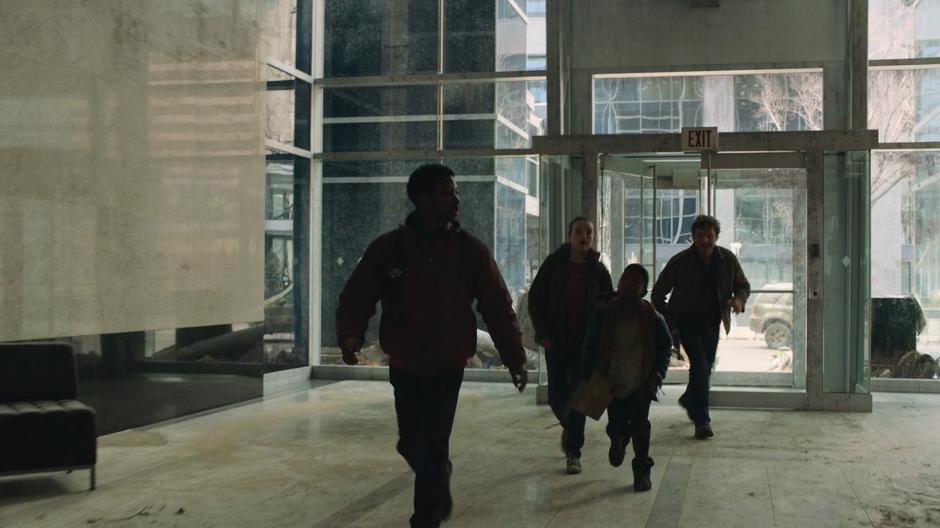 Henry leads Ellie, Sam, and Joel into the bank's lobby.