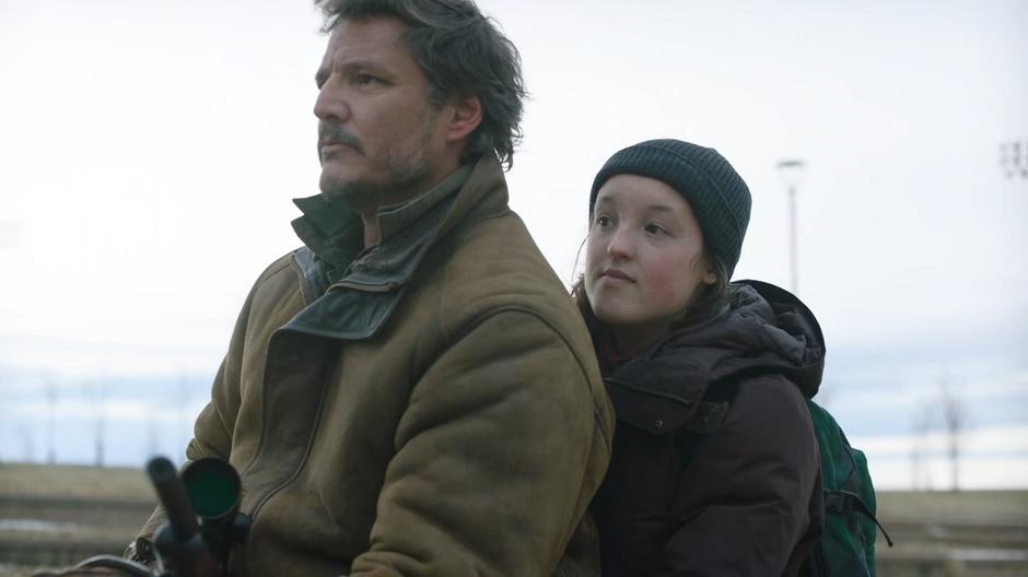 Joel and Ellie look at the sign with the Firefly symbol painted on it.