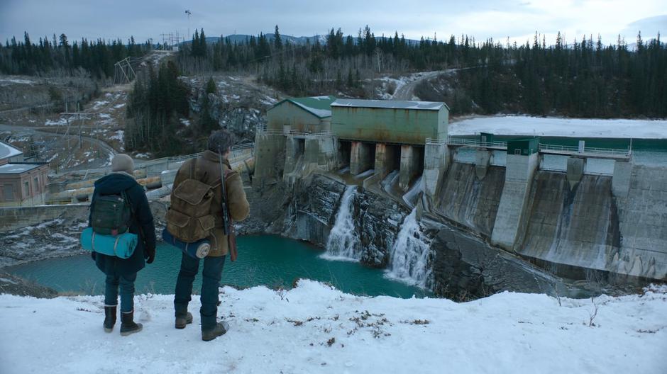 Ellie and Joel arrive at the top of the rise and look over the old dam.