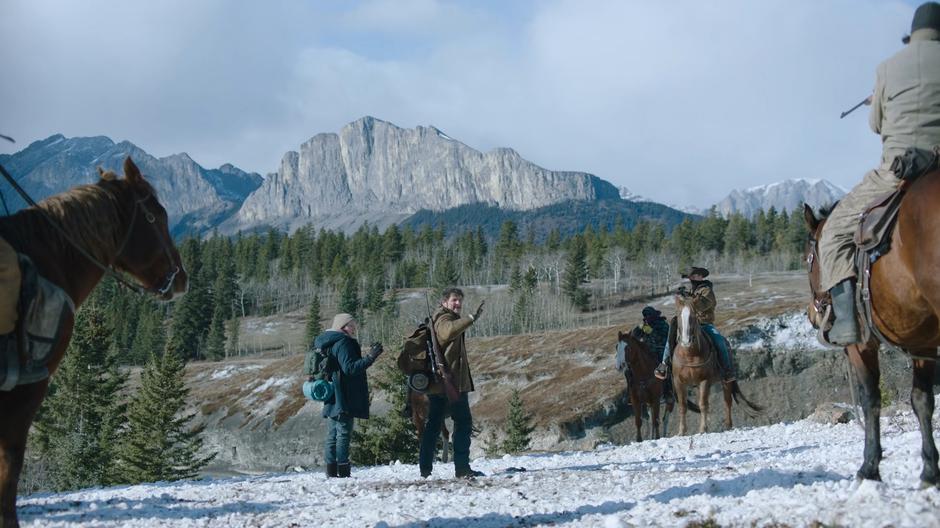 Joel and Ellie look around at the riders holding them at gunpoint and Joel tries to explain that they are just passing through.