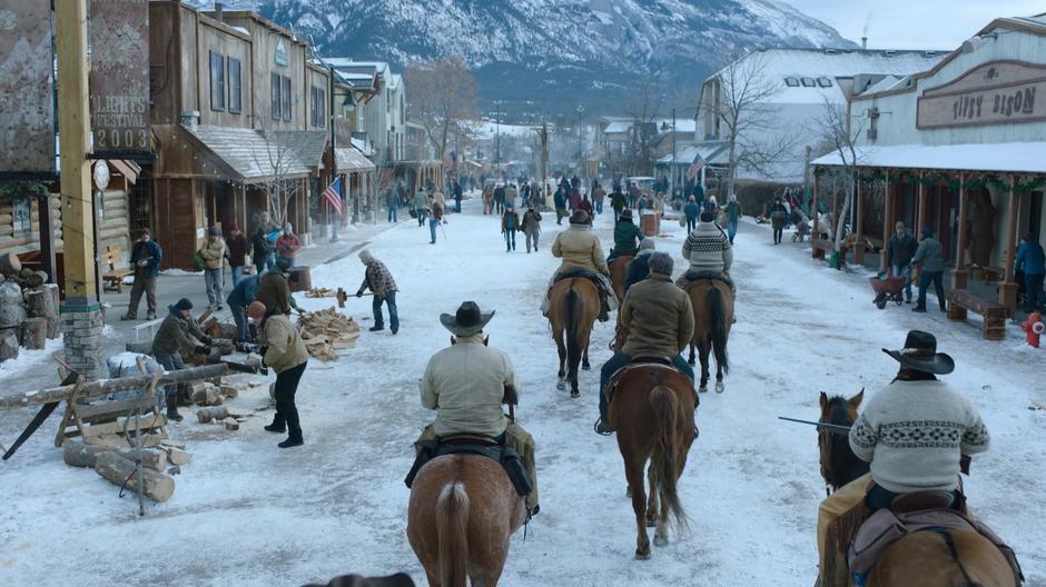 The patrol surrounds Joel and Ellie as they all ride into the busy town.