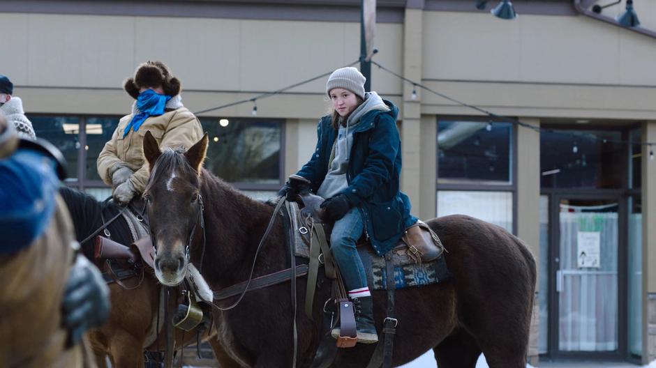 Ellie sits on the horse watching Joel and Tommy's reunion.