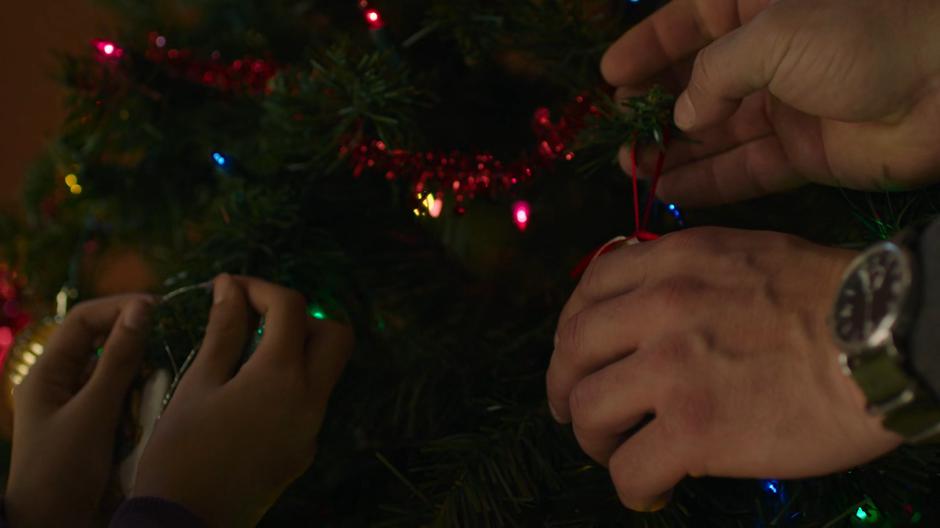 Sarah and Joel hang ornaments on their Christmas tree.