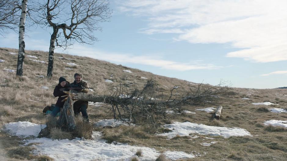 Joel reaches for the rifle to switch places with Ellie and show her how it is done.