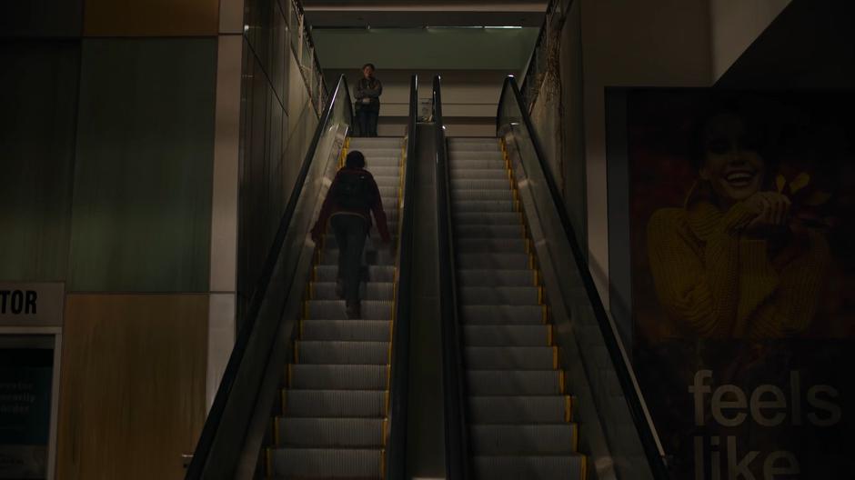 Riley watches from above as Ellie plays around on the escalator.