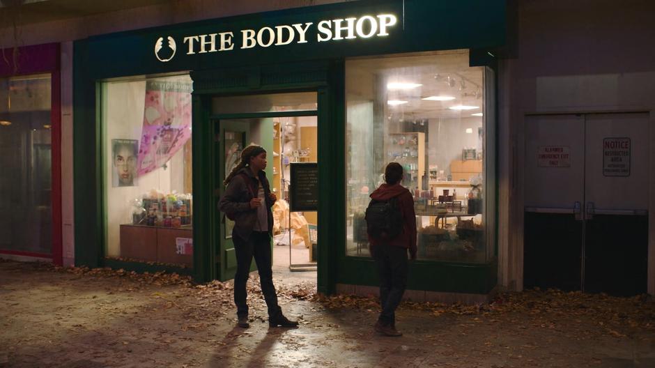 Riley and Ellie look at a Body Shop while talking about whay people looted after Outbreak Day.