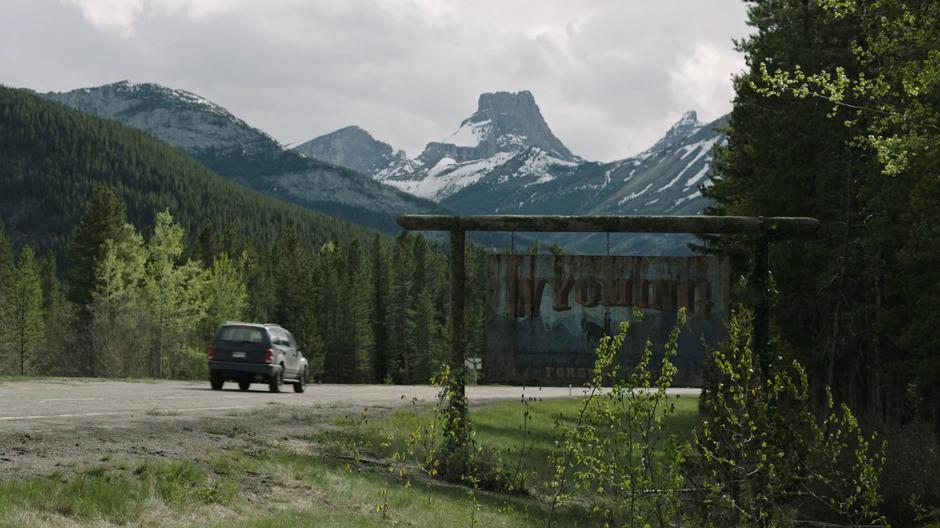 Joel and Ellie drive past a Welcome to Wyoming sign.