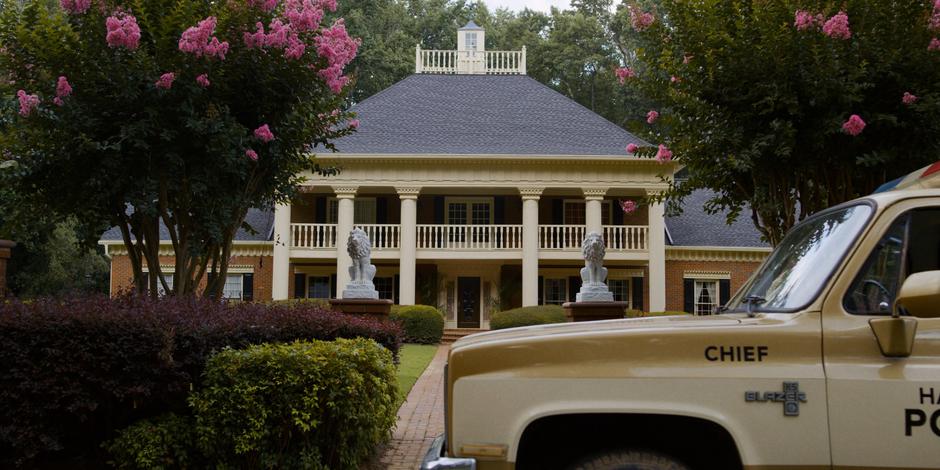 Hopper pulls his police truck in front of the mansion.