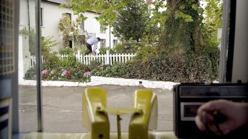 The Doctor jumps a fence to get into a house.