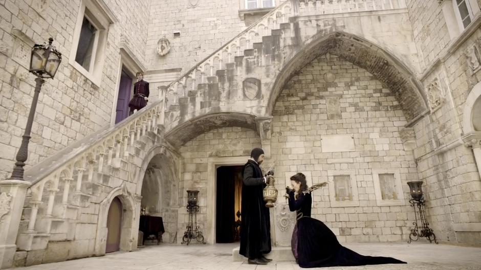 Rosanna takes a drink from her steward while Francesco walks down the stairs.