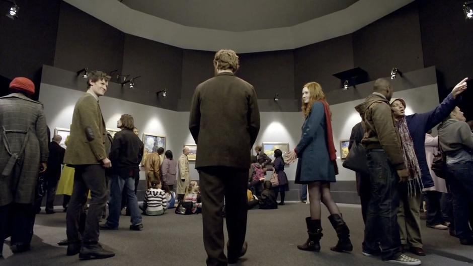 Amy and the Doctor show Vincent into the exhibit of his work.