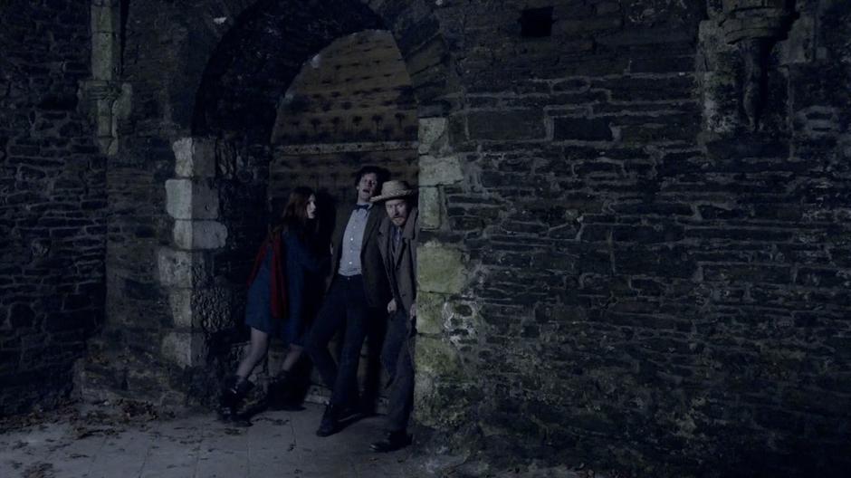 Amy, Vincent and the Doctor push the door of the crypt closed behind them.