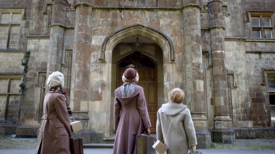 Madge, Lily, and Cyril stand out front of the mansion.