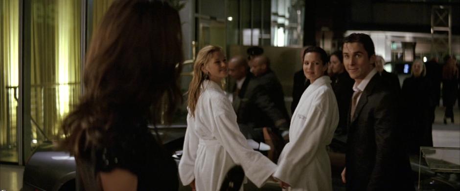 Bruce turns to talk to Rachel Dawes while leaving the hotel with his two companions.