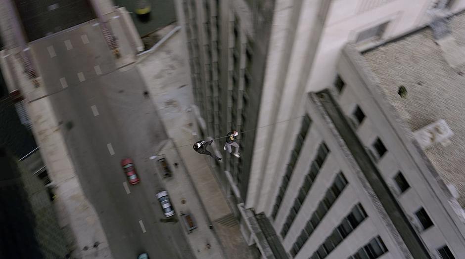 Two masked criminals zip-line over to the bank.