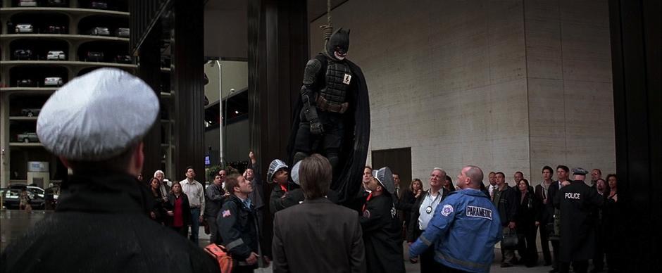 The police pull down the murdered fake-Batman in front of a crowd.