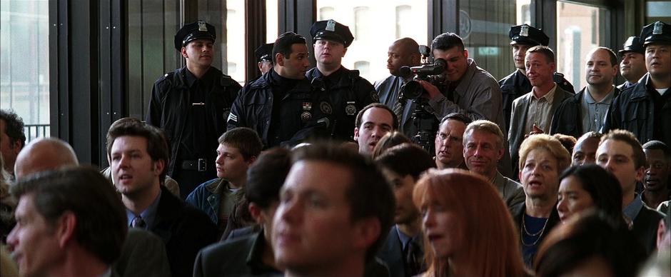 Police and press watch Harvey Dent's press conference.