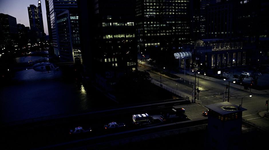 The police convoy drives across a bridge while being followed by a police helicopter.