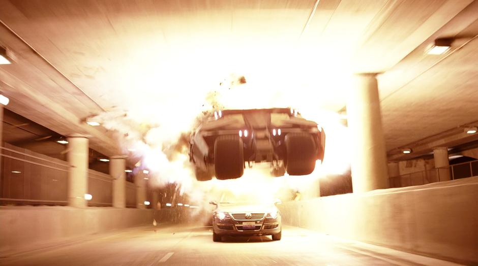 Batman jumps over another car while chasing the convoy.
