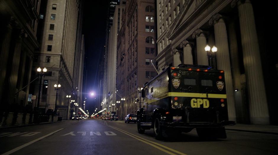 The armored car carrying Harvey Dent drives down the street while a helicopter flies from the other direction.