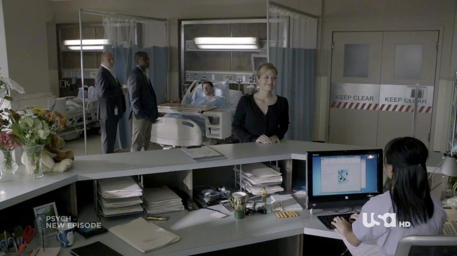 Juliet talks to the desk nurse while Henry and Gus talk to a bedridden Shawn.