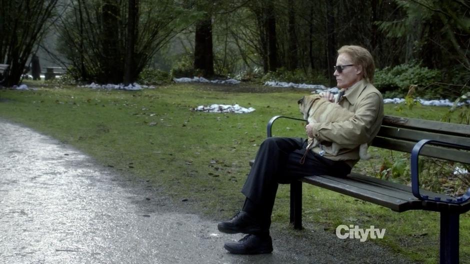 Anson Carr sits on a bunch petting his dog and watching couples by the lake.