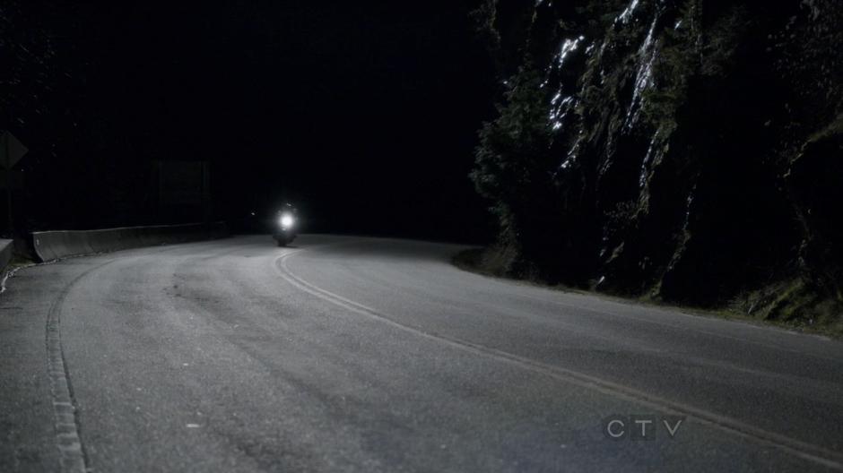 Emma and August drive around a bend in the road.