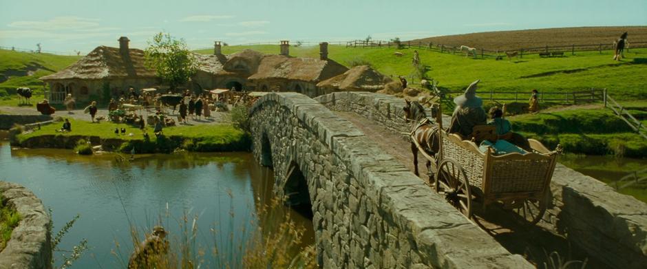 Frodo and Gandalf cross the bridge in Hobbiton.