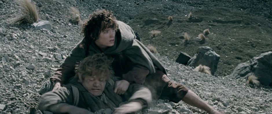 Frodo attempts to pull Sam out of the gravel before the soldiers see them.