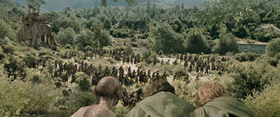 Frodo, Sam, and Gollum watch the army of Harad walk past with the Oliphants.