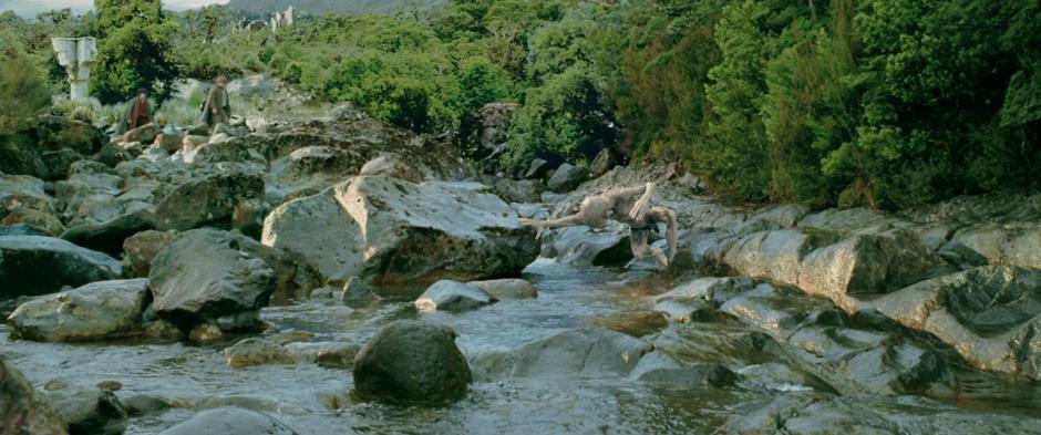 Frodo and Sam walk past the stream while Gollum attempts to catch a fish.