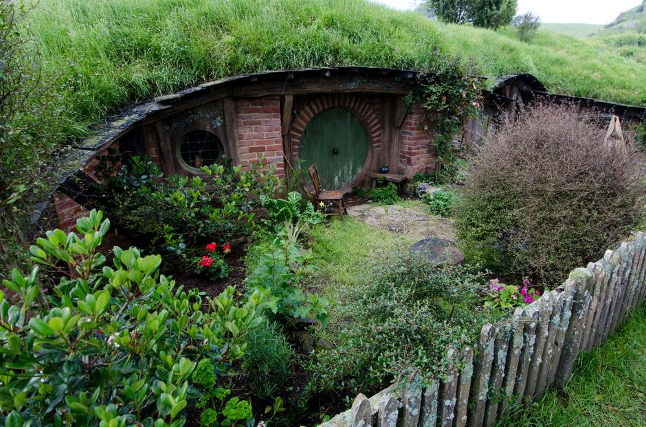 A brick walled hobbit-hole with a green door.