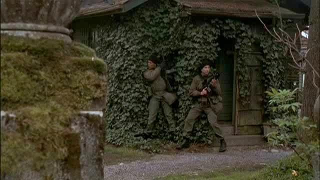 Teal'c and another soldier take cover by the gatehouse.