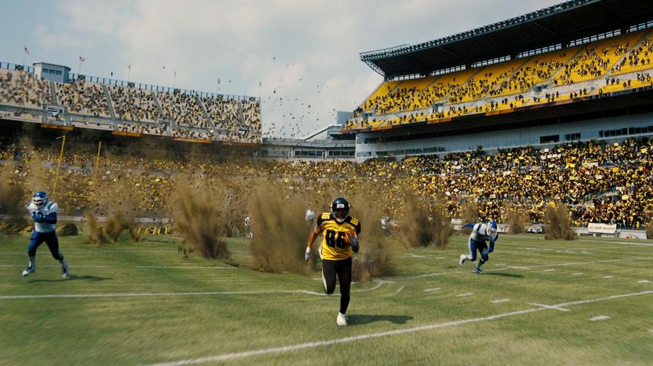 One of the football players runs away from the exploding field.