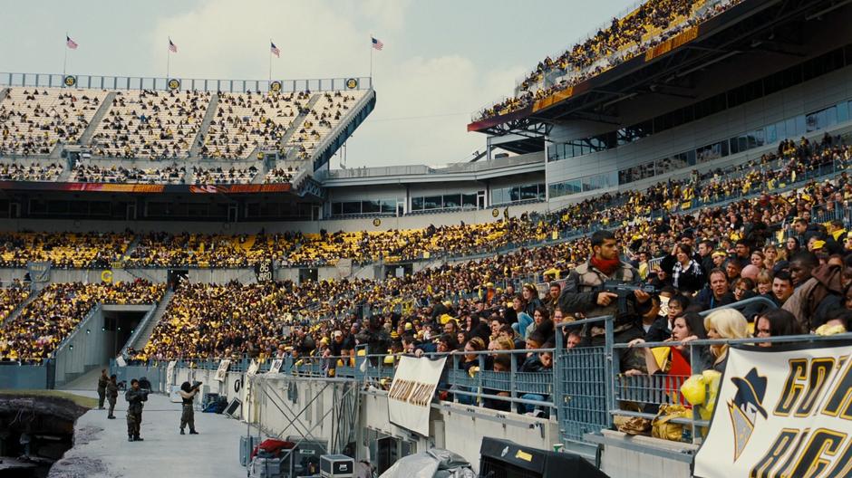 Bane's thugs keep an eye on the crowd while Bane gives his speech.