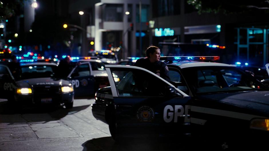 A GPD officer gets out of her car while dozens more pull up behind to surround Batman in the alley.