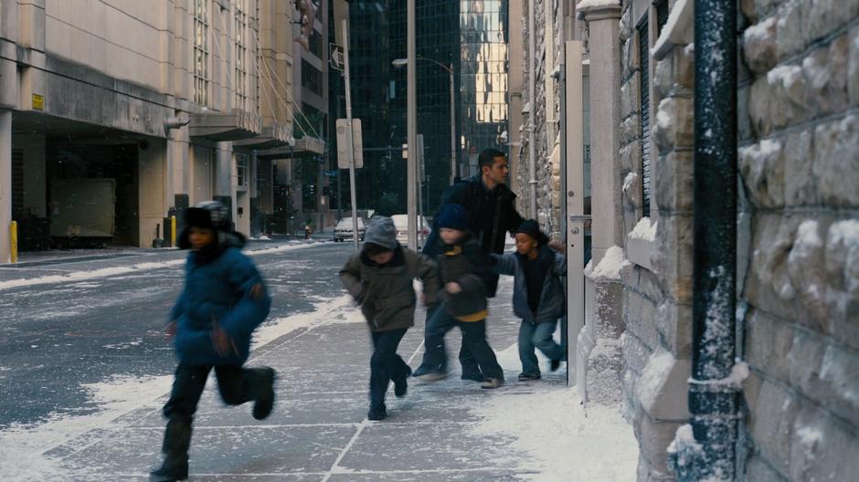 Blake leads the orphans out of building and into a school bus.