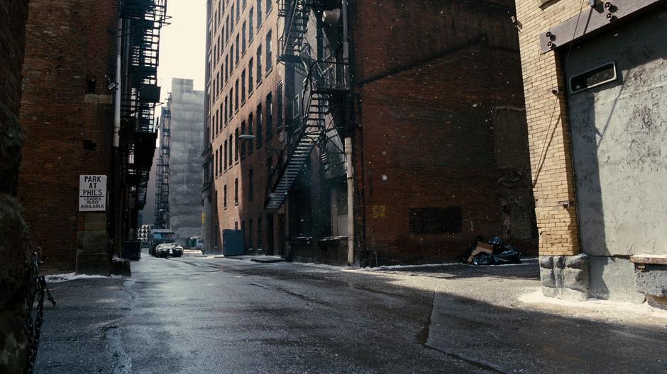 A tumbler and one of the decoy bomb trucks drives down the alley.