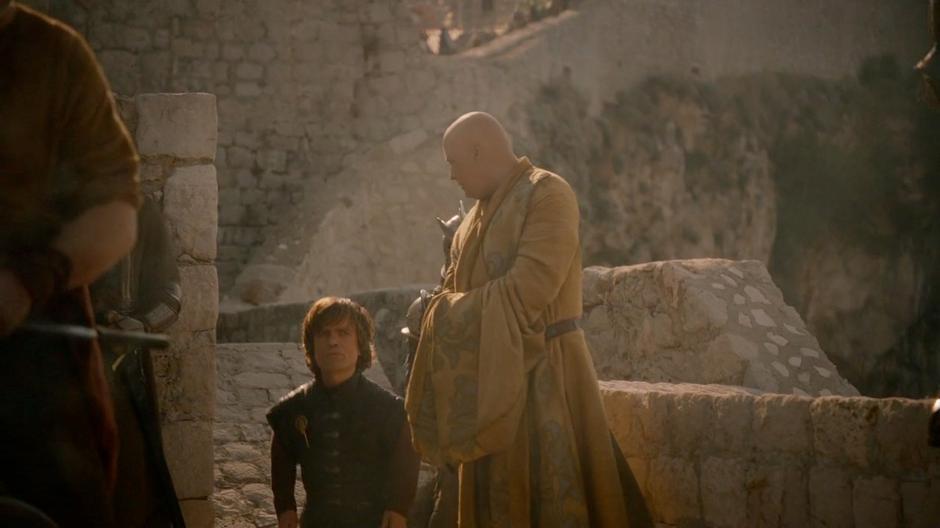 Tyrion and Lord Varys climb the stairs onto the city wall.