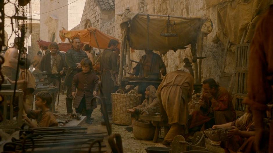 Tyrion and Bronn see a man speaking on some steps.