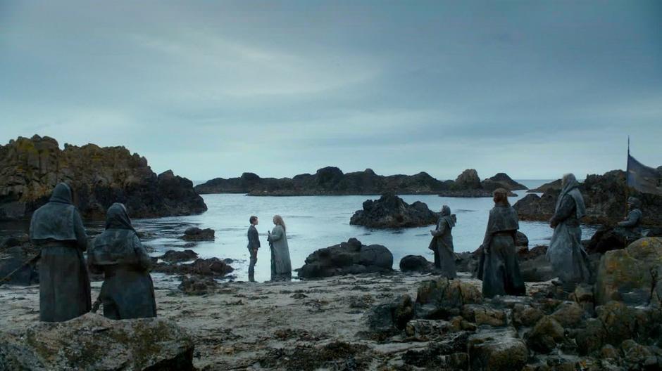 Theon is led through the ceremony by a priest of the Drowned God.