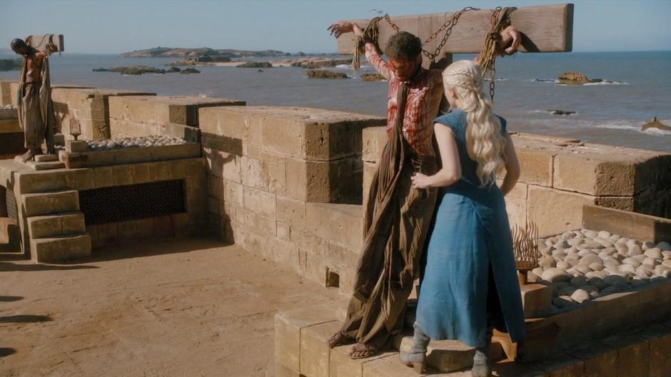 Daenerys approaches one of the slaves tied up to die.