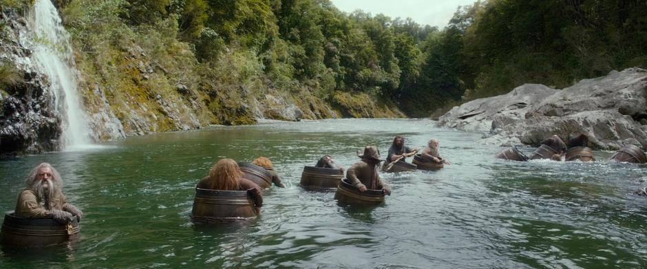 The dwarves float to the edge of the river and attempt to get out of the barrels.