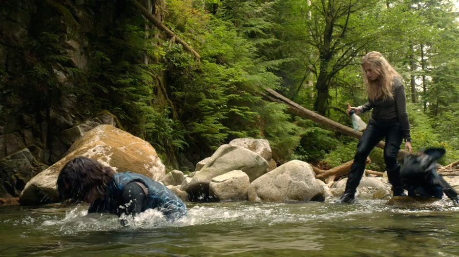 Finn submerges himself in the pool while Clarke collects drinking water.